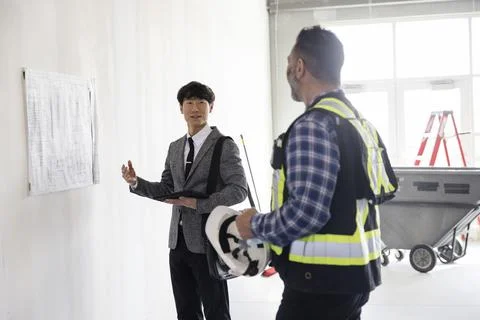 Architect and contractor looking at plans on wall Stock Photos