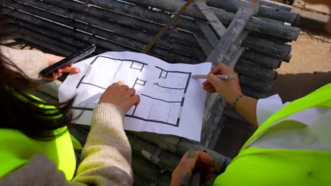 Architect and engineer analyzing a blueprint on a construction site Stock Footage 334632695