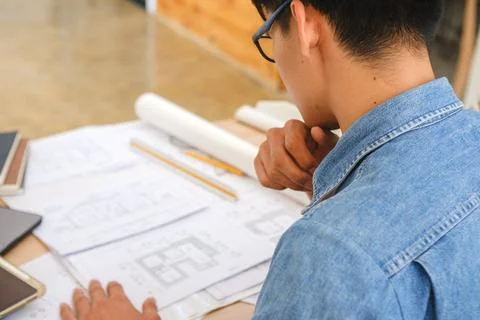 Architect and engineer analyzing blueprints at a work desk in an office Stock Photos