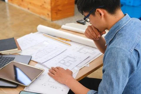 Architect and engineer analyzing blueprints at a work desk in an office Stock Photos