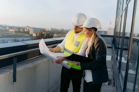 An architect and an engineer are looking at a project on the roof of a buil.. Stock Photos