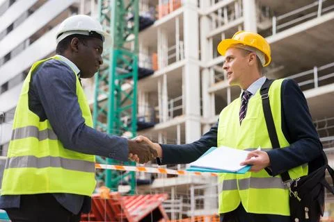 Architect and engineer construction workers shaking hands while working for Stock Photos