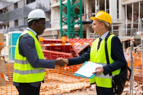 Architect and engineer construction workers shaking hands while working for Stock Photos