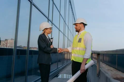 An architect and an engineer shake hands on the terrace of a built office b.. Stock Photos
