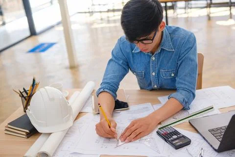 Architect and engineer using a compass to design house plans at a work desk.. Stock Photos