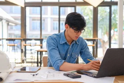 Architect and engineer working on blueprints using a laptop and tablet in ... Stock Photos