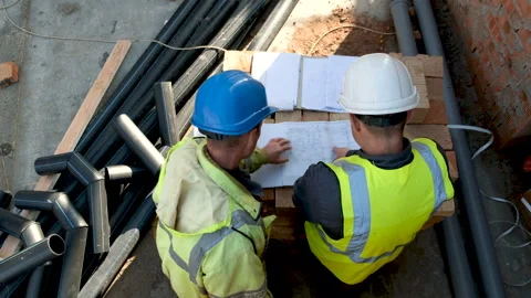 Architect and structural engineer dressed in green work vests and helmets Stock Footage 258112493