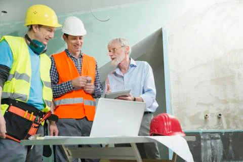 Architect and two construction workers at construction site of new building Fotos de archivo