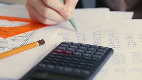 Architect with blueprint and calculator estimating project cost in her office Stock Footage 72830617