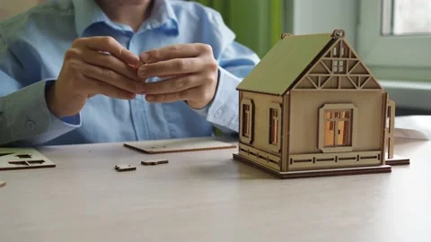 An architect boy collects a model of a house made of plywood. the hands of a boy Stock Footage 166234015