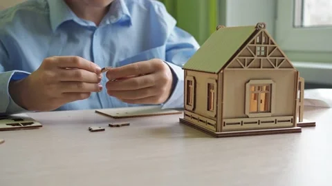 An architect boy collects a model of a house made of plywood. the hands of a boy Stock Footage 167559516