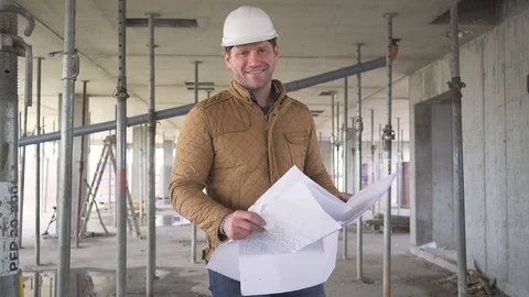 Architect browsing building project indoor of construction, smiling to camera. Vídeos de archivo 72358292