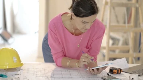 Architect browsing internet on tablet and writing data on the project, steadycam Video stock 76516987