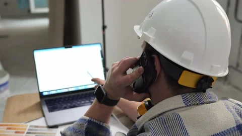 Architect checks drawings using a laptop and talks on the phone Video stock 234217122