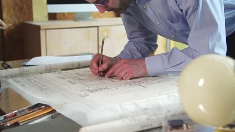 The architect-designer makes notes in pencil on the construction plan. Stock Footage 180532262