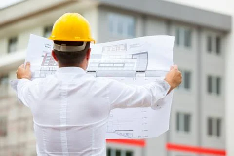 Architect designing a building standing on construction site Stock Photos