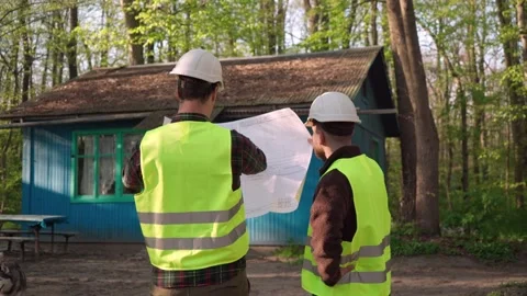 The architect discusses with the builders the plan for the house Stock Footage 241177824