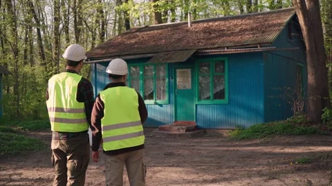 The architect discusses with the builders the plan for the house. outdoors Stock Footage 241492961