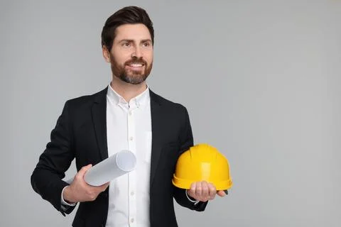 Architect with draft and hard hat on gray background, space for text Stock Photos