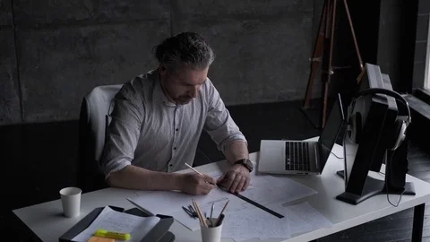Architect draws a plan on paper at the desk in a cozy office. Stock Footage 107330168