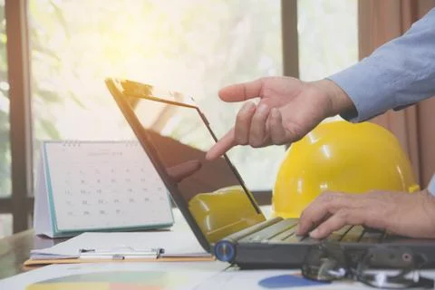 Architect engineer using laptop for working with yellow helmet on desk. Foto stock