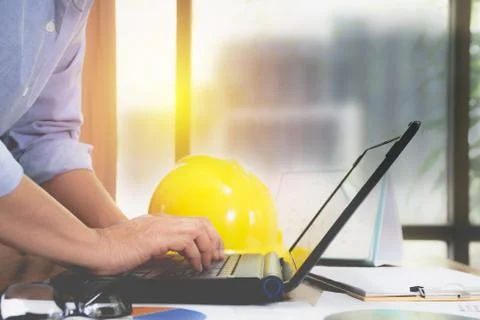 Architect engineer using laptop for working with yellow helmet on desk. Foto stock