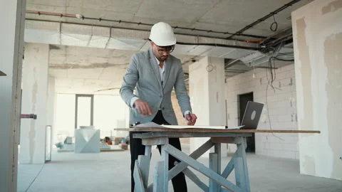 Architect evaluating blueprints and pointing in building under construction Stock Footage 312832938
