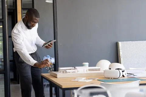 Architect examining scale model and using tablet in modern office, copy space Stock Photos