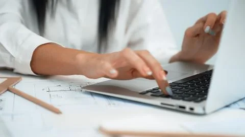 Architect hand using laptop with blueprint placed on table. Closeup. Immaculate. Foto stock