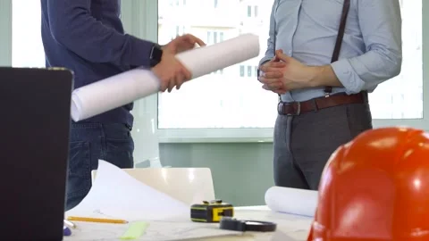 Architect hands over building plans to his colleague in a modern office Stock Footage 311990992