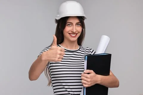 Architect in hard hat with draft and folder showing thumbs up on light grey.. Stock Photos