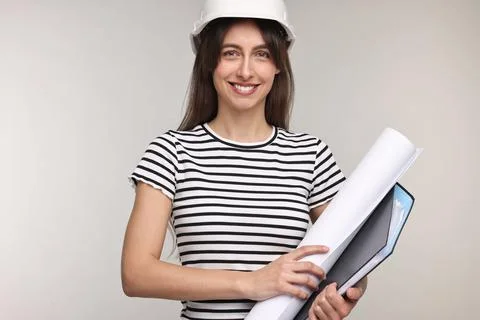 Architect in hard hat with draft and folder on light grey background Stock Photos