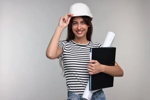 Architect in hard hat with draft and folder on light grey background Stock Photos