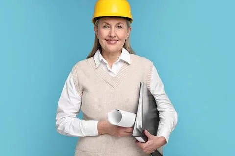 Architect in hard hat with draft and folder on light blue background Foto stock