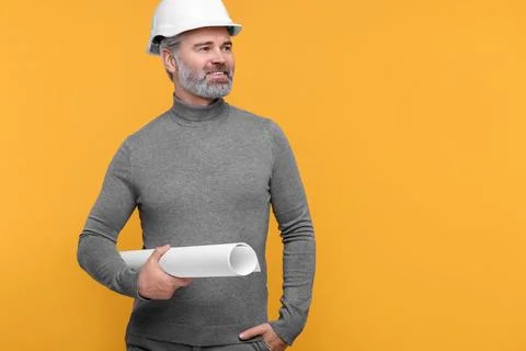 Architect in hard hat holding draft on orange background. Space for text Stock Photos