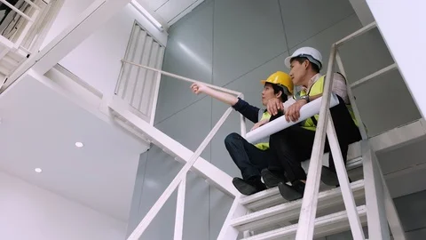Architect hold blueprint and engineer sit stairs talking about project problem. Stock Footage 129066350