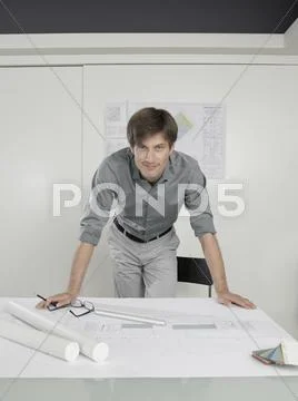 An architect leaning over blueprints on a desk Stock Photos