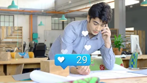 Architect leaning over plans marking while phone heart counter rising above Stock Footage 333396804