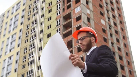 Architect looking at building plans with new construction. Slow motion Stock Footage 77510009