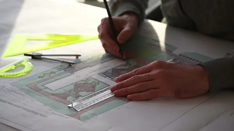 Architect makes corrections on drawing at table with pencil and ruler Stock Footage 143481924