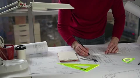 Architect makes corrections on drawing at table with pencil and ruler Stock Footage 143482048