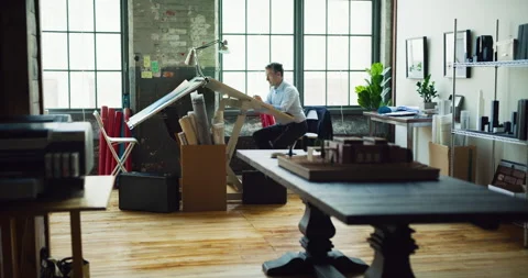 Architect man sits at drafting table in modern industrial office during the day. Stock Footage 199461245