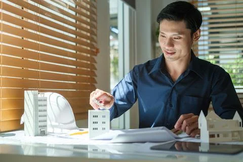 Architect man working on a construction project and examining model of a re.. Stock Photos