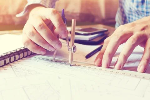 Architect man working with drawing compass on blueprints paper on desk offi.. Stock Photos