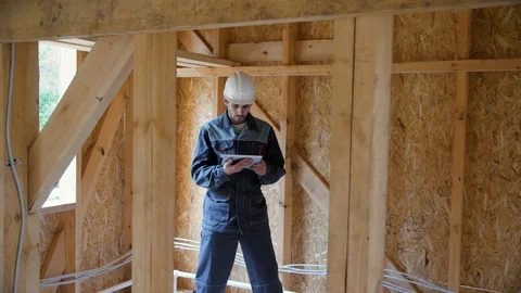 Architect or builder check plans in a half built timber frame house. Engineer on 動画素材 96891274