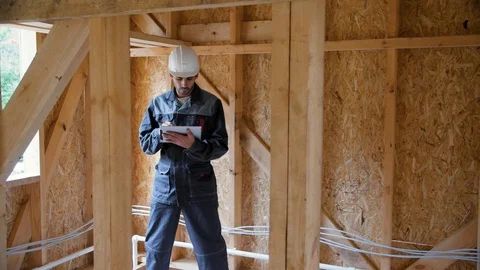 Architect or builder check plans in a half built timber frame house. Engineer on 動画素材 96891912