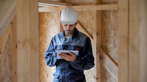 Architect or builder check plans in a half built timber frame house. Engineer on 스톡 동영상 96892634