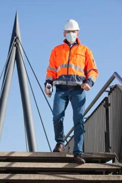 Architect or engineer with face mask and protective clothing walking downstai Фото