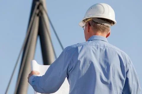 Architect or engineer reading a construction plan in front of industrial back 写真素材