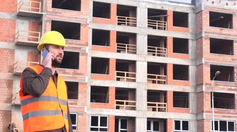 Architect outside apartment building talking smartphone to real estate developer Stock Footage 58513869